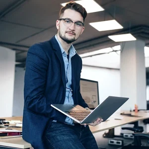 Hombre de negocios en su oficina con una laptop en la mano